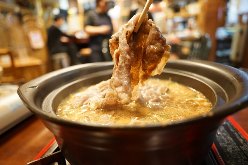 鍋から肉を持ち上げ
