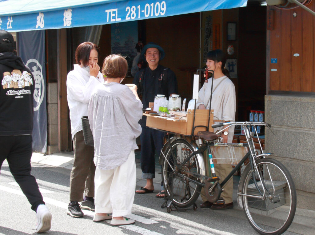 この日お披露目となった「イチバイク」。荷台の什器にチャイなどを載せて移動販売する〈ヒュッティ―〉（右）と、什器製作者の〈木犀〉（中央奥）