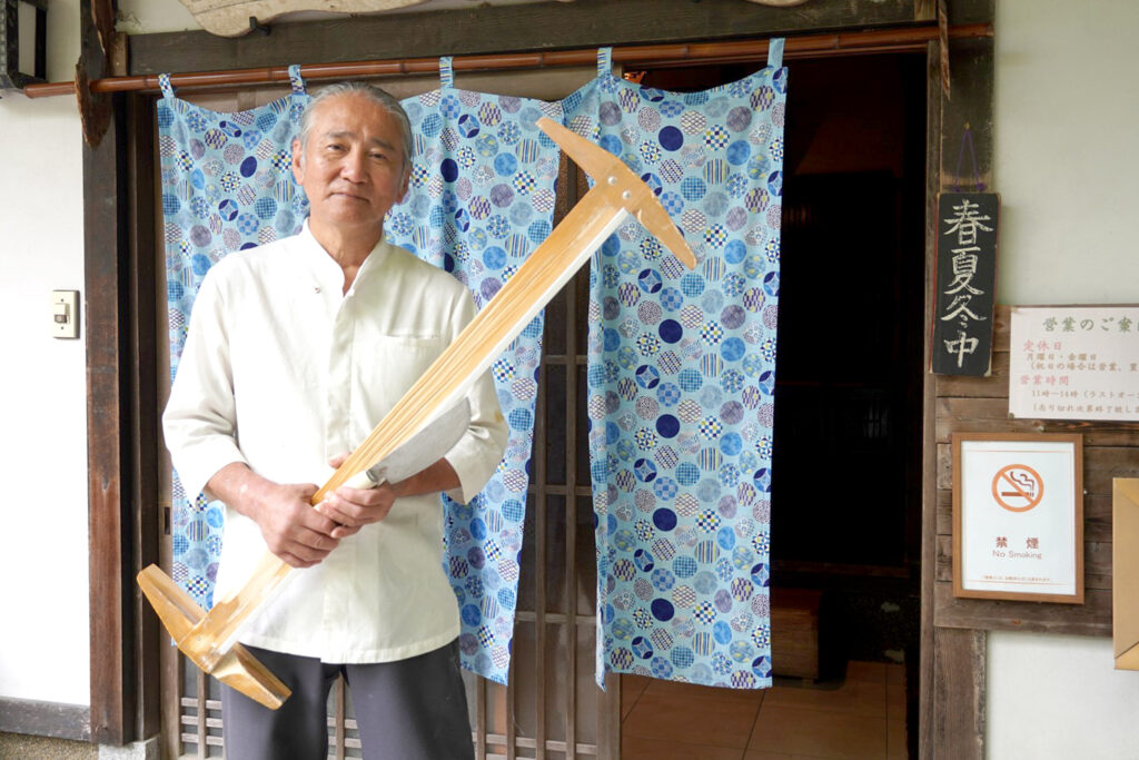 自分で開発した道具を持つ店主の小川俊和さん