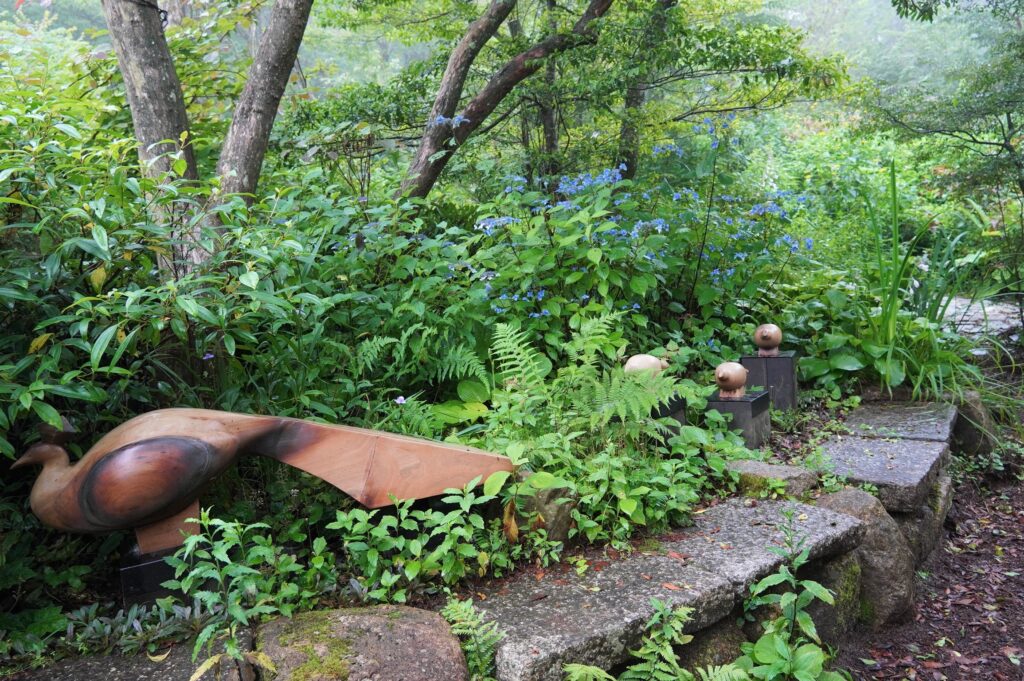 草花の間に隠れている木製の鳥